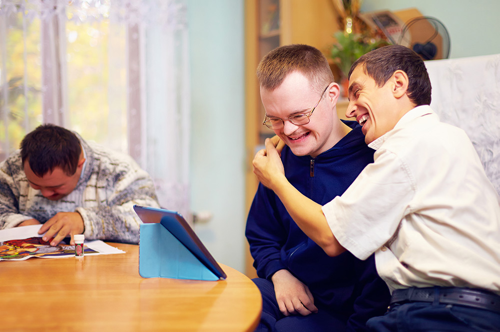 Carer with young man with disabilities laughing