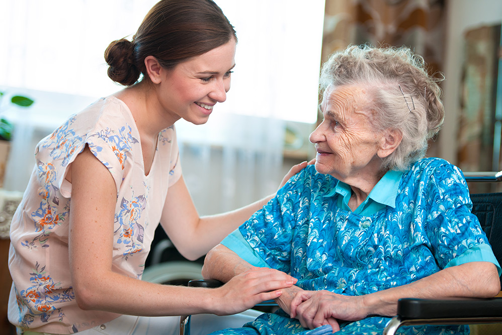 Women carer with elderly woman smiling